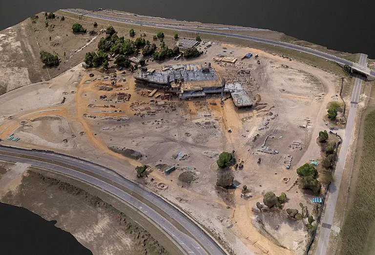 Aerial view of a large construction site with partially built structures and surrounding roads.