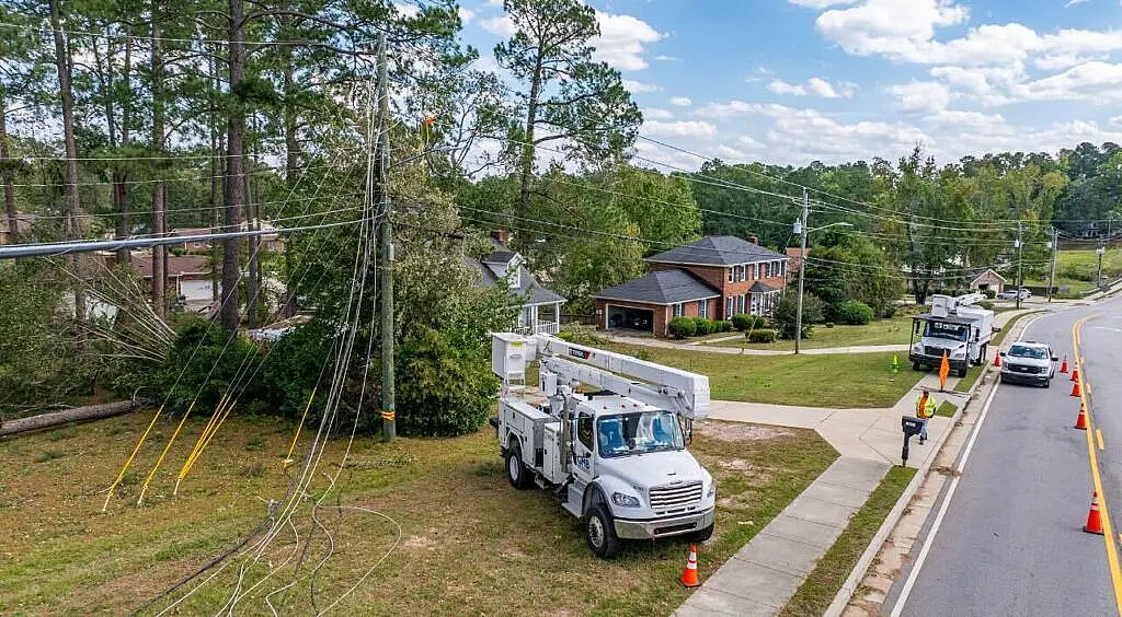 Utility truck working on power lines in a suburban neighborhood.