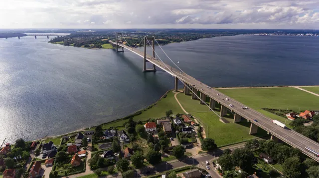 A large bridge spanning a body of water with houses nearby.