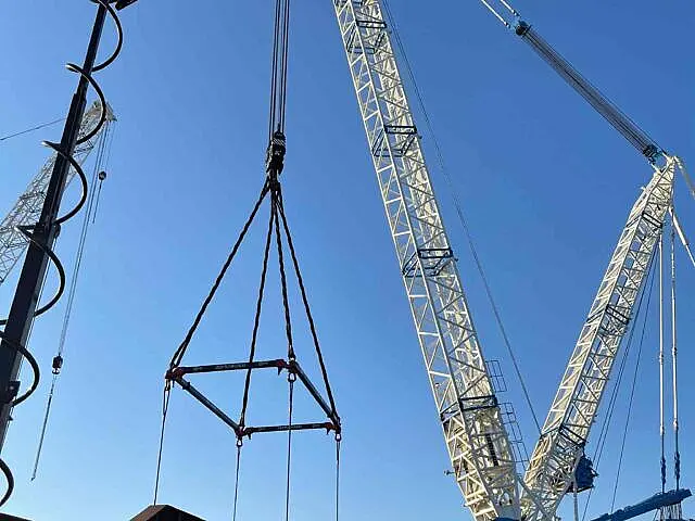 Heavy lift crane operation at industrial job site lifting large steel structure