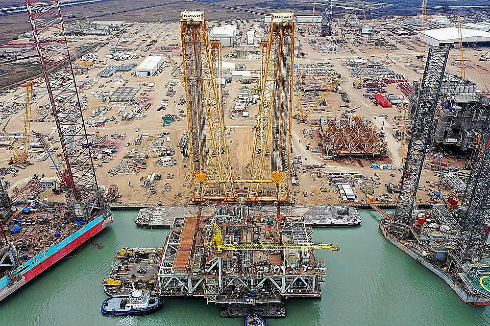 Heavy lift crane operation at construction site with dual cranes performing coordinated lift for industrial project in Texas